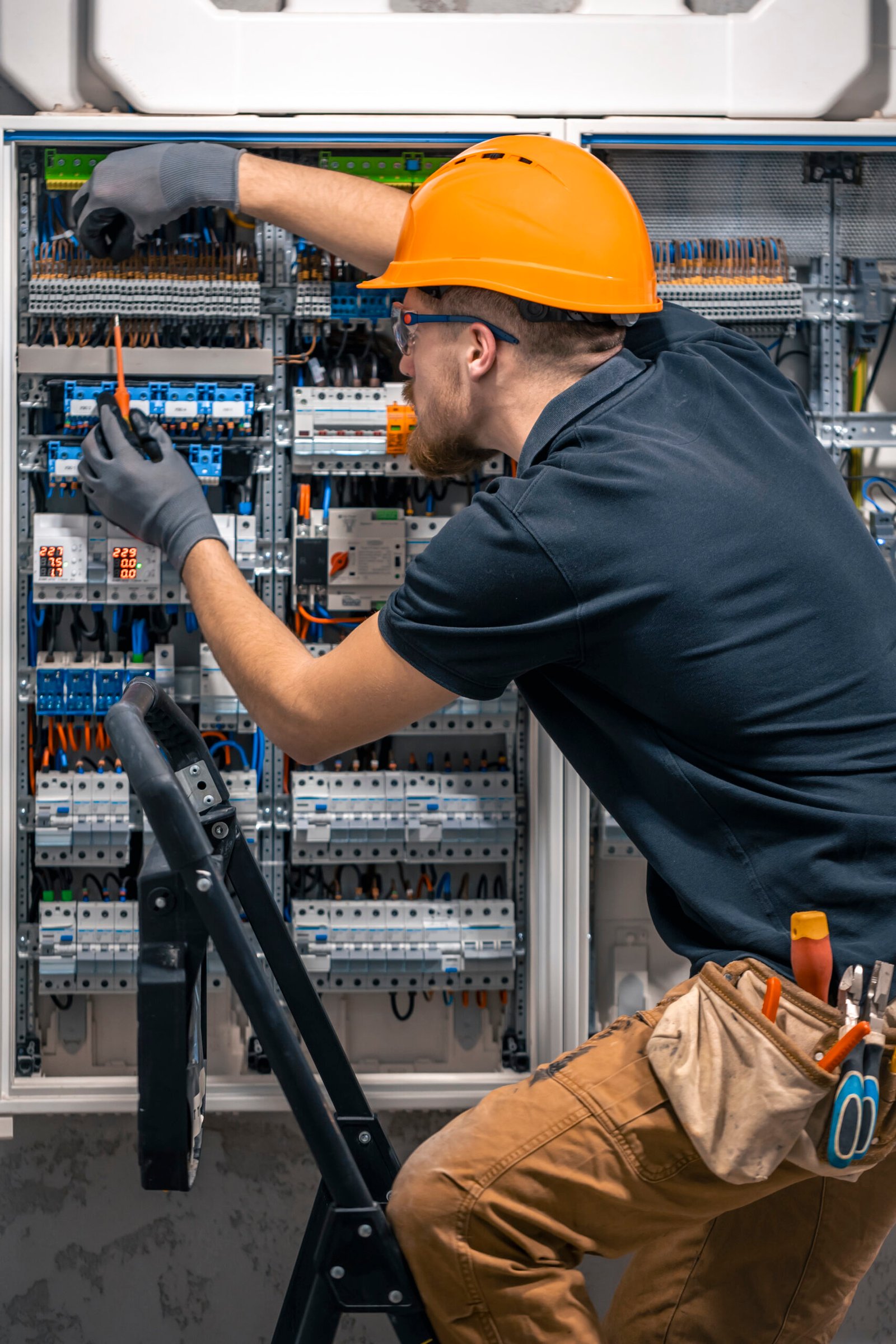 Male electrician working in a switchboard with fuses. Male electrician working in a switchboard with fuses. Installation and connection of electrical equipment. Professional with tools in hand.